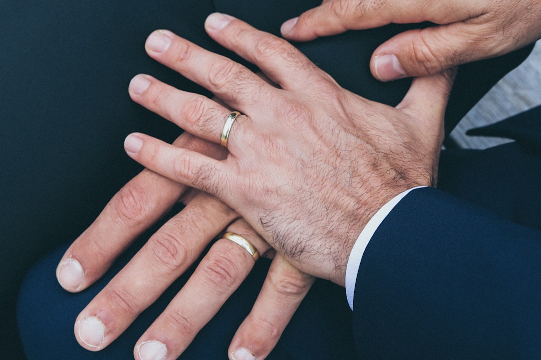two-mans-hands-wearing-gold-colored-wedding-rings-DUK7XiBpGSY