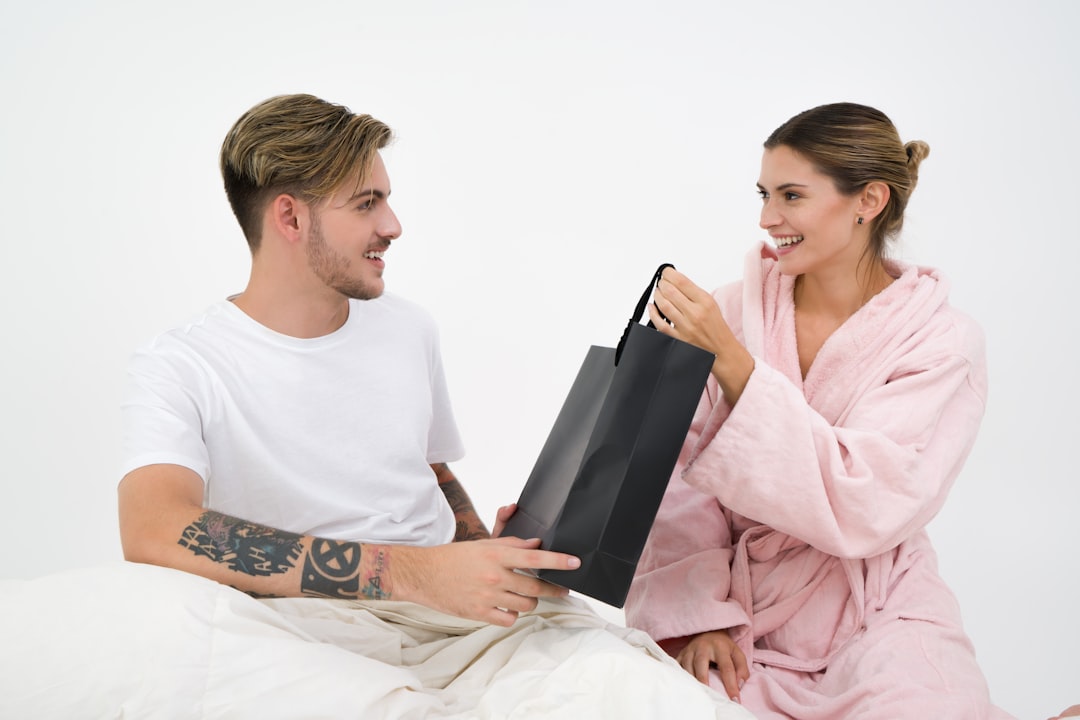 woman-holding-black-paper-bag-sitting-in-front-of-the-man-CePzL5MMNpE