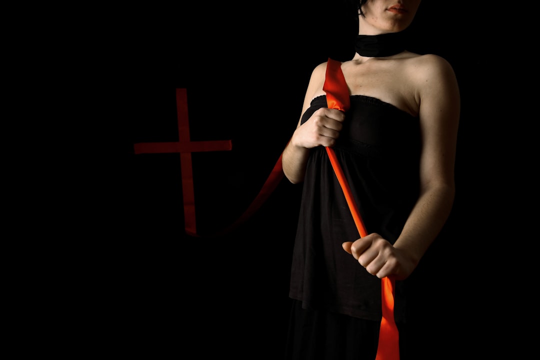woman-in-black-spaghetti-strap-dress-holding-red-and-black-stick-ZoqVHlv79-o
