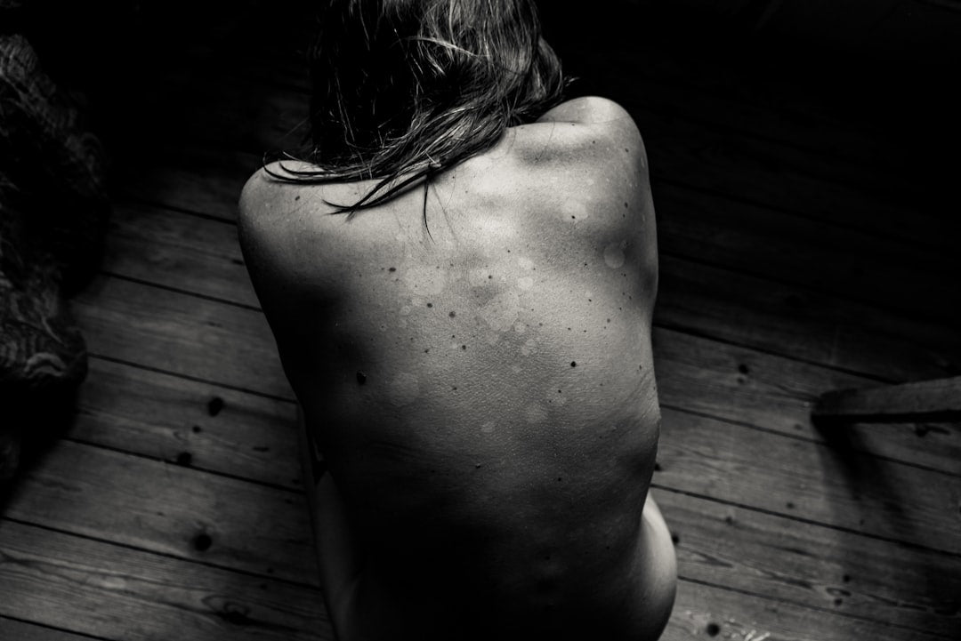 a-naked-man-sitting-on-a-wooden-floor-oL1CNLhNrX8