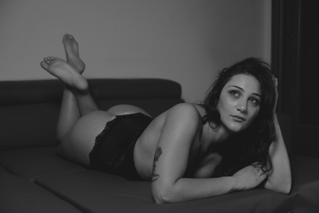 a-black-and-white-photo-of-a-woman-laying-on-a-couch-QqzSuGPsCj4