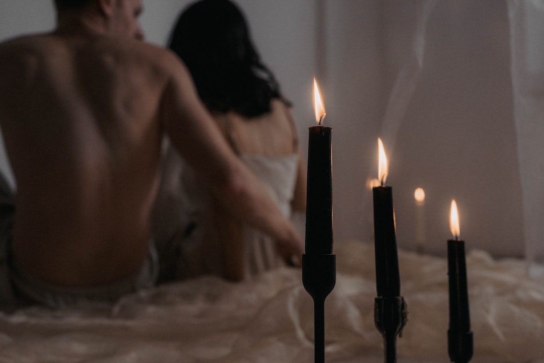a-man-and-woman-sitting-on-a-bed-next-to-candles-rcP0uT9FTYE