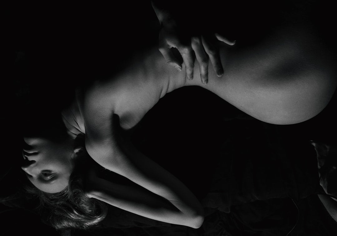 a-woman-laying-on-top-of-a-bed-in-the-dark-rzABsNF_wJo