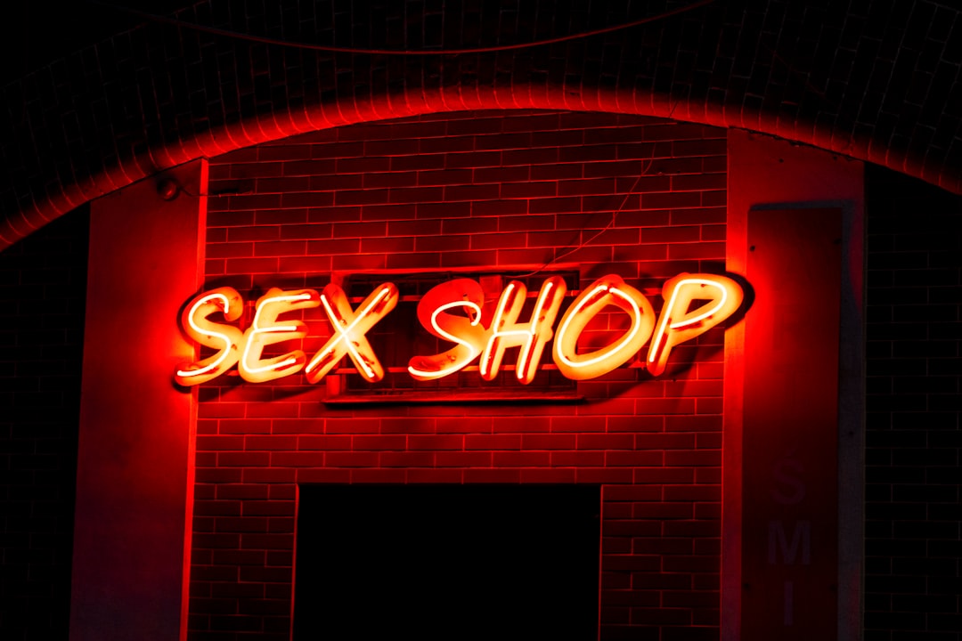 a-neon-sign-that-reads-sex-shop-on-a-brick-wall-JrU5vtntsHY
