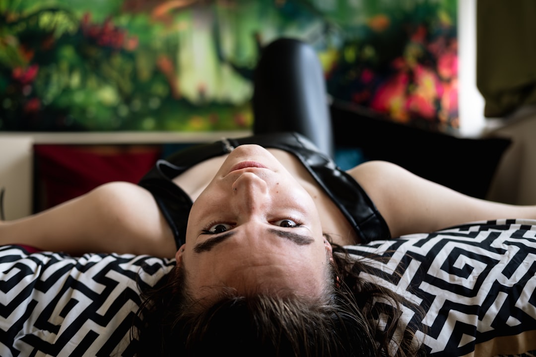 a-woman-laying-on-top-of-a-bed-next-to-a-painting-LG0WygRT7QI