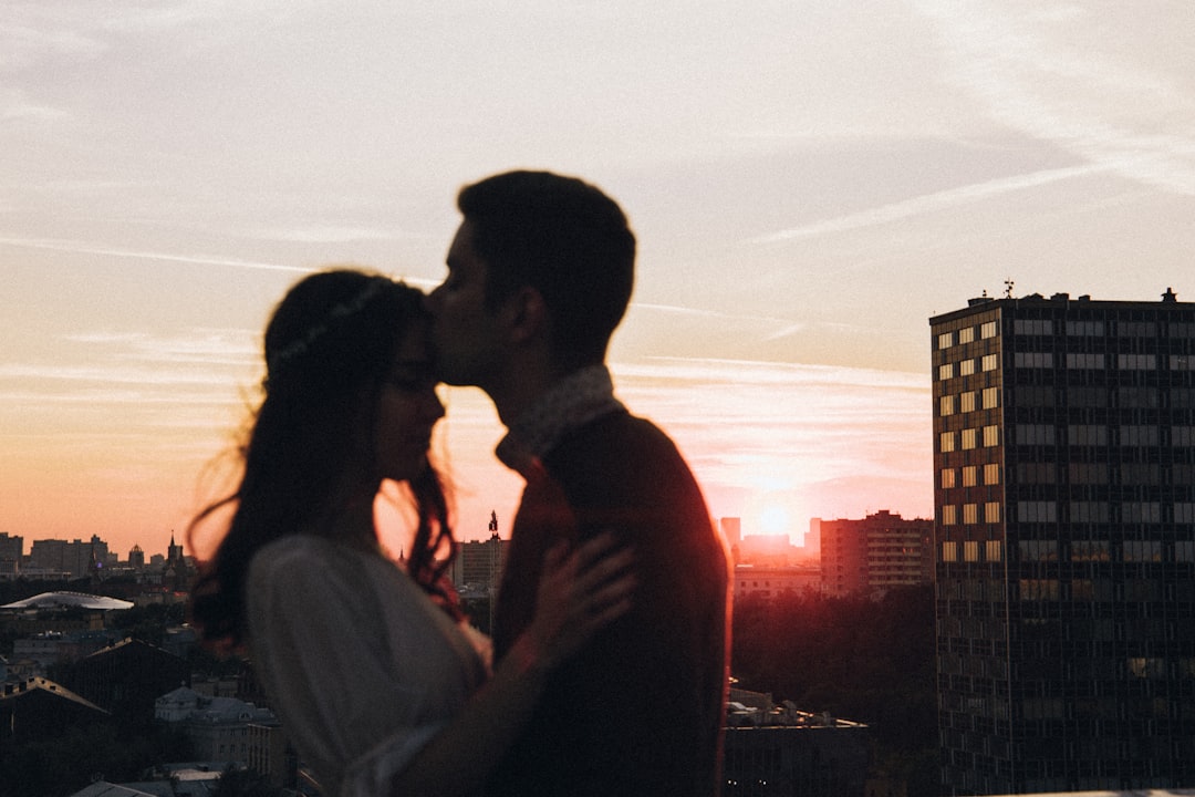 a-man-and-a-woman-kissing-in-front-of-a-sunset-puw9mQRp2wo
