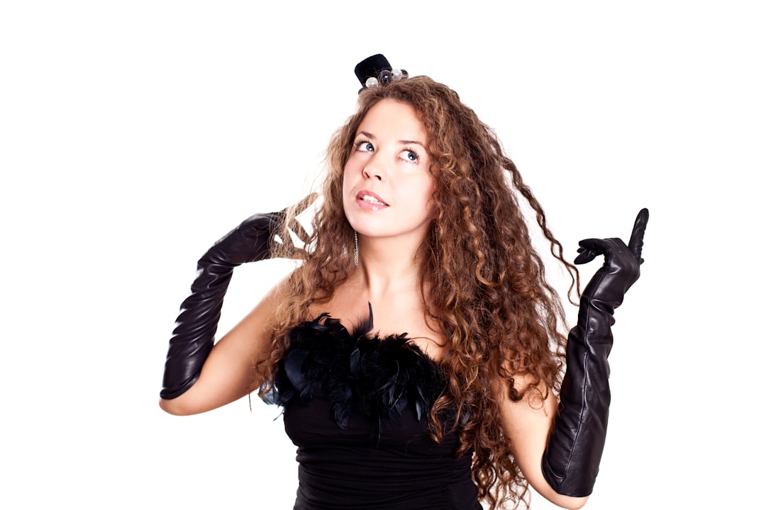 a-woman-in-a-black-dress-holding-a-pair-of-gloves-S8Owr5GWdxk