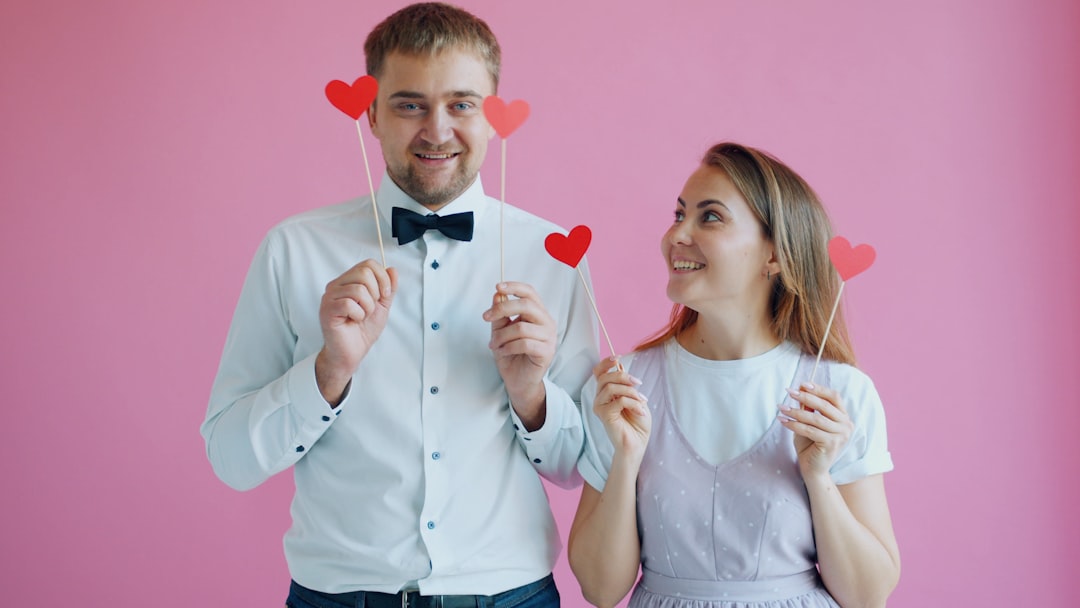 couple-holding-red-hearts-on-sticks-1l2-JL9f1pg